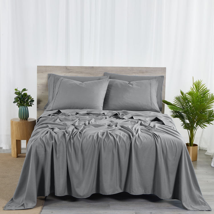 A charcoal grey 6 piece bamboo sheet set displayed on a bed, including a fitted sheet, a flat sheet, and pillow covers with a second pillow placed on the bed.