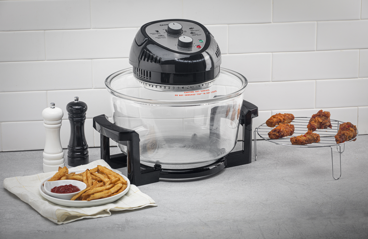 Black and clear air fryer on a kitchen counter with fries and chicken.