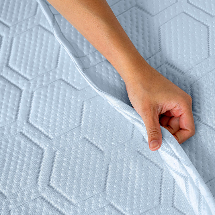 Hand holding a textured mattress corner