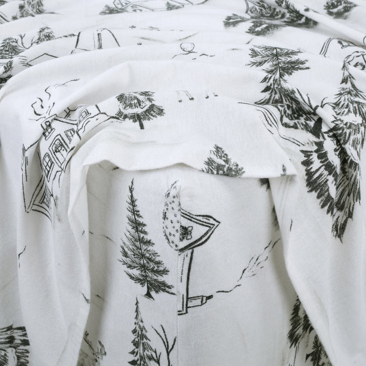 White fabric with black nature-themed illustrations, including trees and houses.