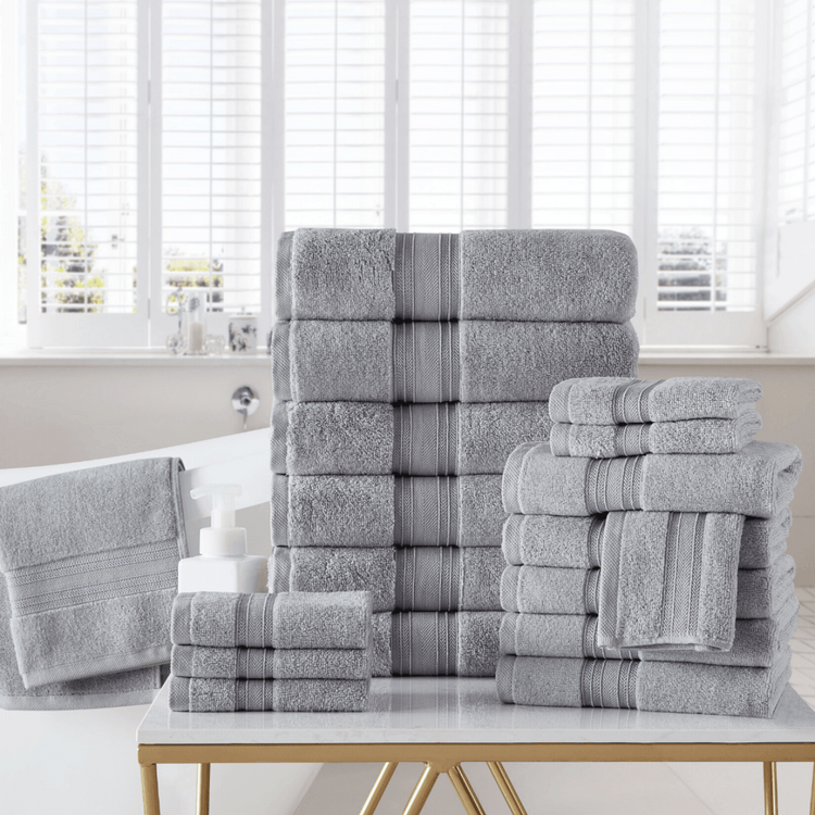 Stack of gray towels with striped patterns on a white surface in a bright room.
