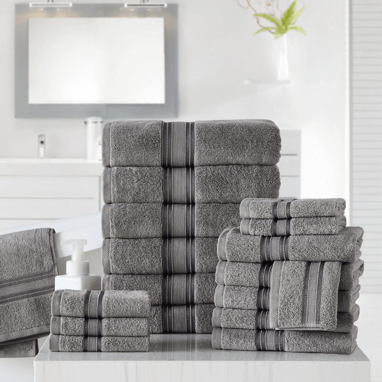 Stack of gray towels with striped patterns on a white surface.