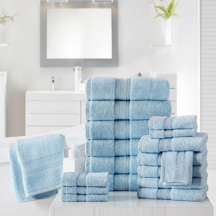 Set of light blue towels on a white surface with a mirror and plant in the background.