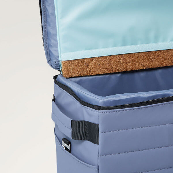 Blue Nutshell Cooler with open lid showing interior coconut fiber insulation on a light gray background