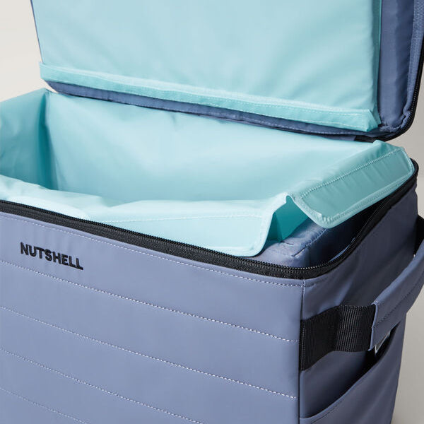 Blue cooler bag with open lid showing teal interior removable welded liner, branded 'Nutshell'.