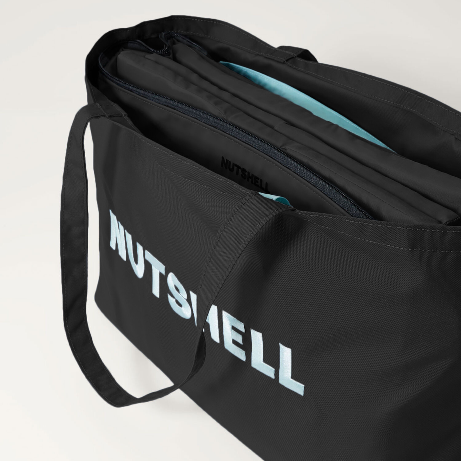 Black tote bag with 'NUTSHELL' embroidery on a light gray background