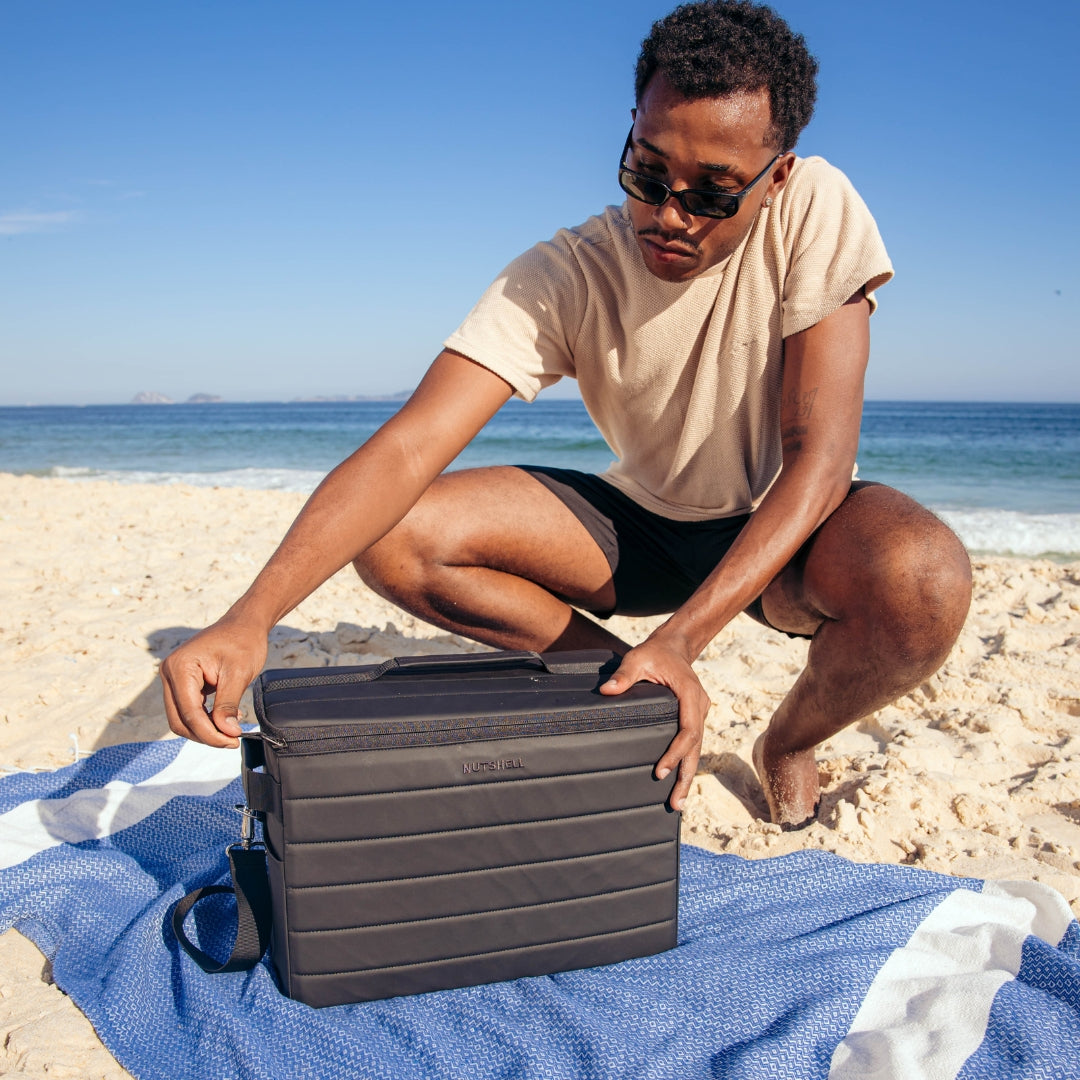 Man opening Nutshell Cooler zipper at the beach