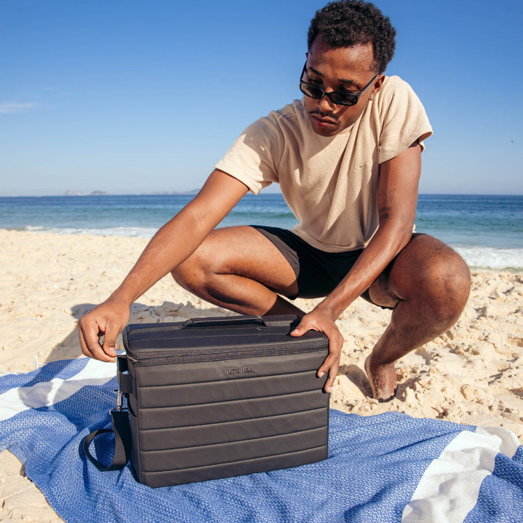 Man opening Nutshell Cooler zipper at the beach