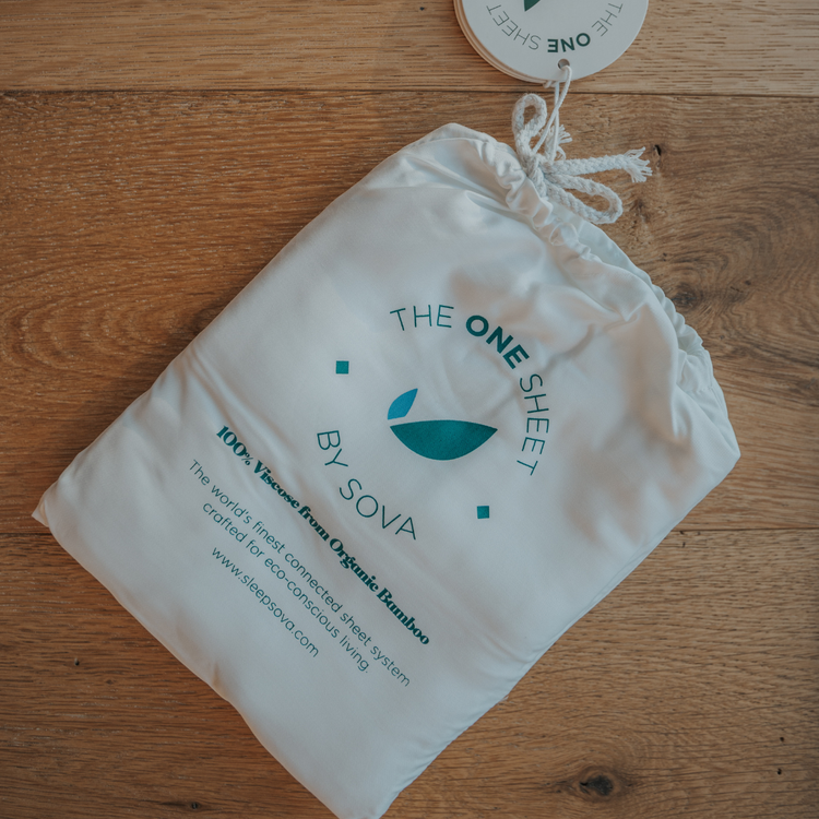 White drawstring bag with 'The One Sheet by Sova' branding on a wooden surface