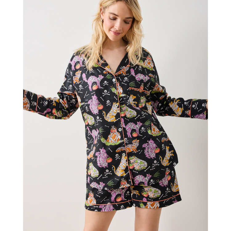 Woman wearing a black pajama set with colorful animal pattern on a white background