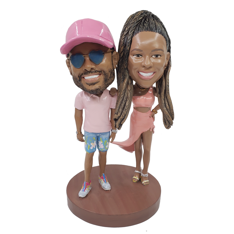 Bobblehead figures of a man and woman in pink outfits on a white background