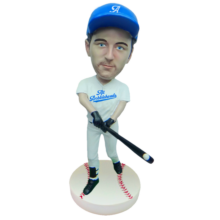 Bobblehead of a baseball player in a blue cap and white uniform with 'All Schlockheads' text, holding a bat on a white background.