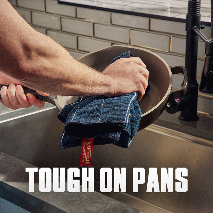 Person drying a pan with a blue towel in a kitchen, with 'Tough on Pans' text overlay.