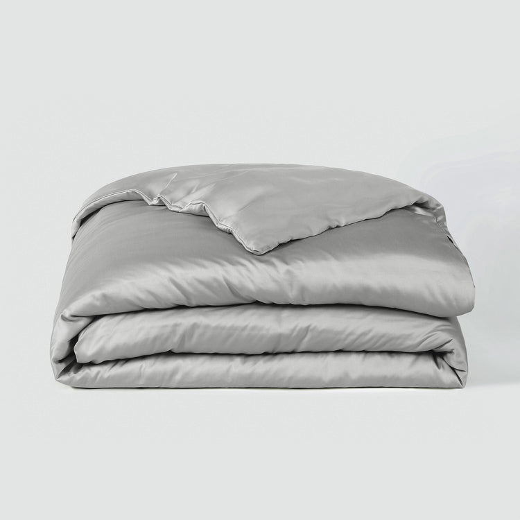 Folded light gray comforter on a white background