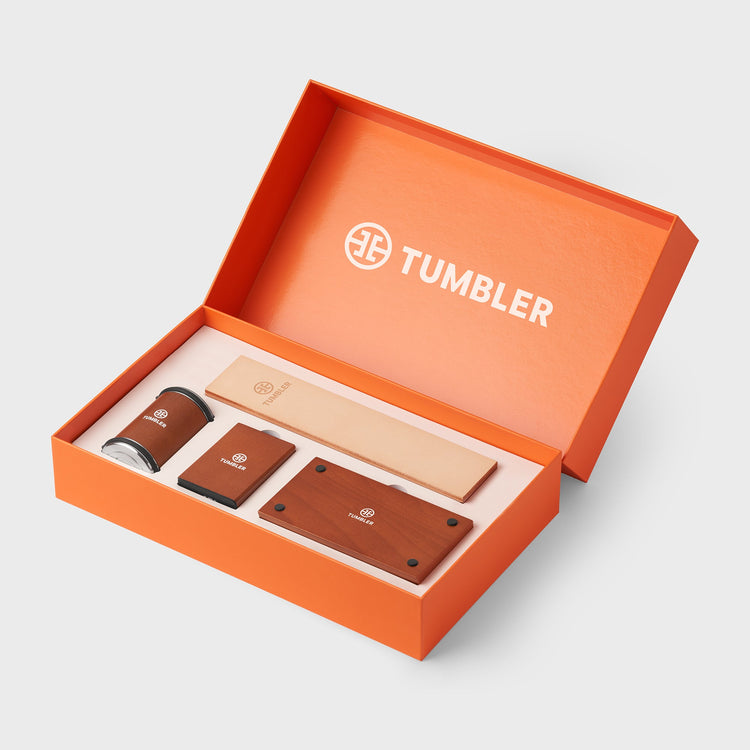 Orange Tumbler packaging box with branded items on a light gray background