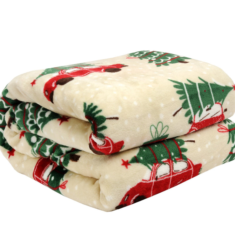 Folded Christmas-themed blanket with trees, reindeer, and stars on a white background