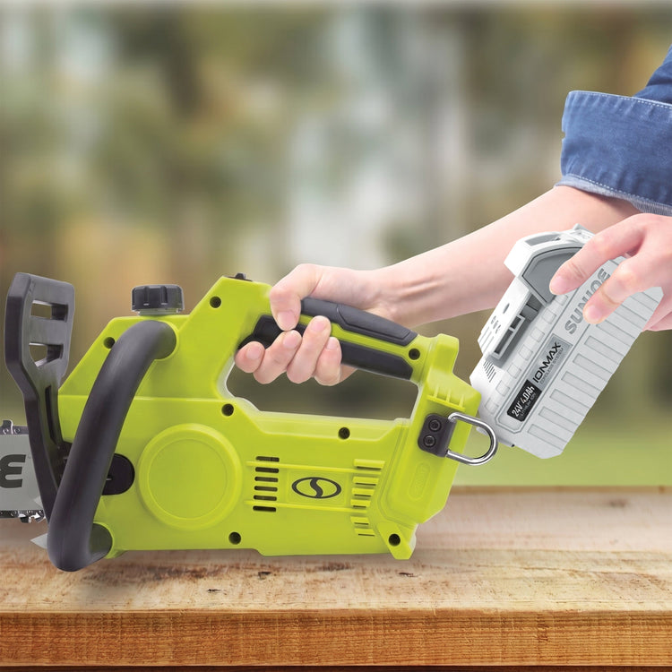 Person holding a green power tool on a wooden surface with a blurred natural background