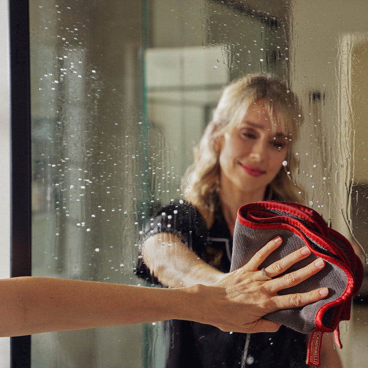 Woman cleaning a mirror with a red and gray cloth