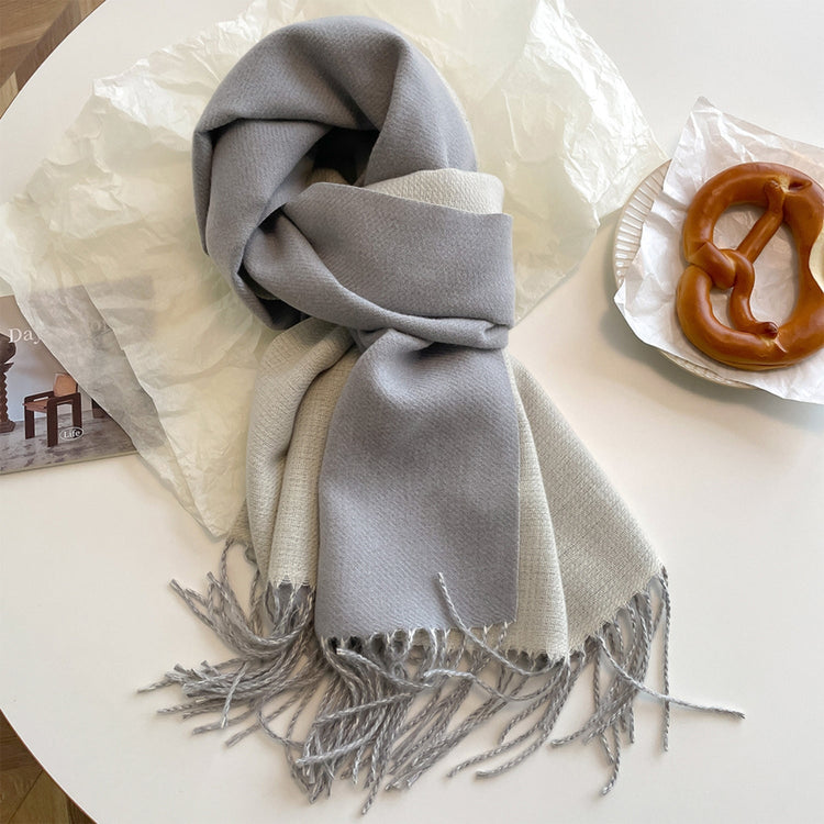 A reversible pashmina scarf in blue and beige with fringe detailing, displayed around a cylindrical object.