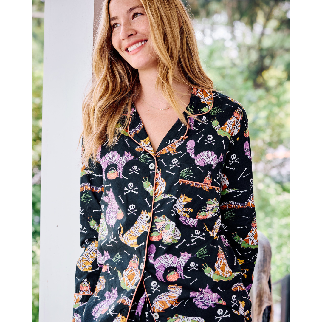 Woman wearing a black pajama top with colorful cat pattern outdoors.