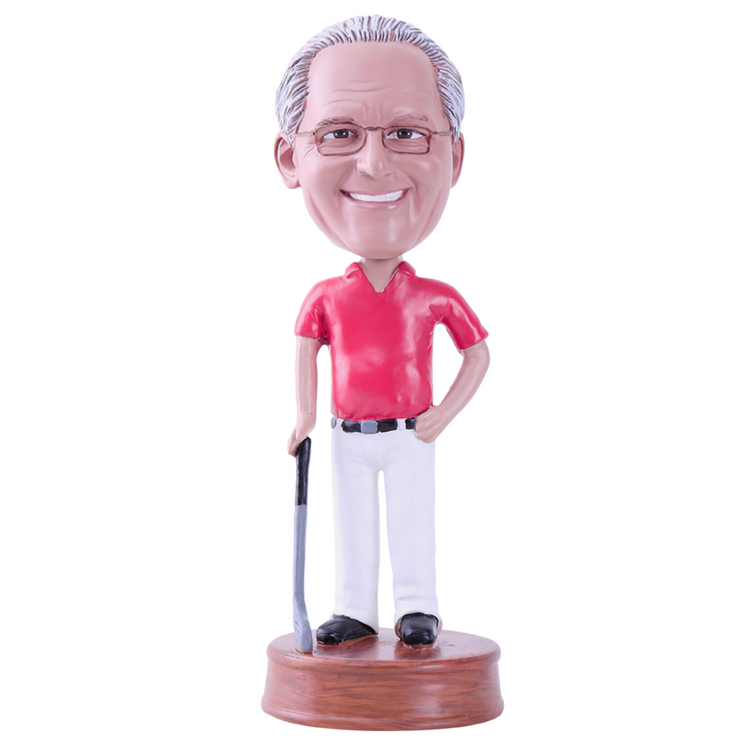 Bobblehead figure of a man in a red shirt and white pants holding a golf club on a wooden base.