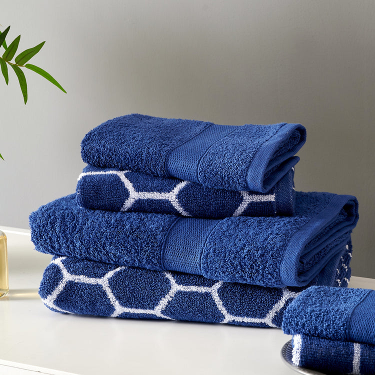 Stack of blue towels with white patterns on a neutral background
