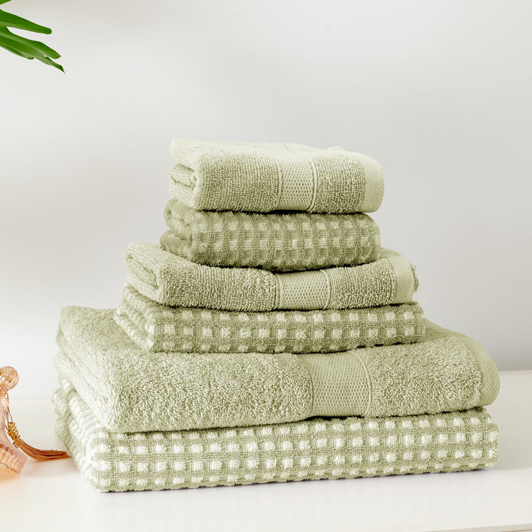 Stack of green towels on a white surface with a light gray background