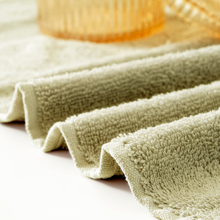 Folded green towel on a light surface