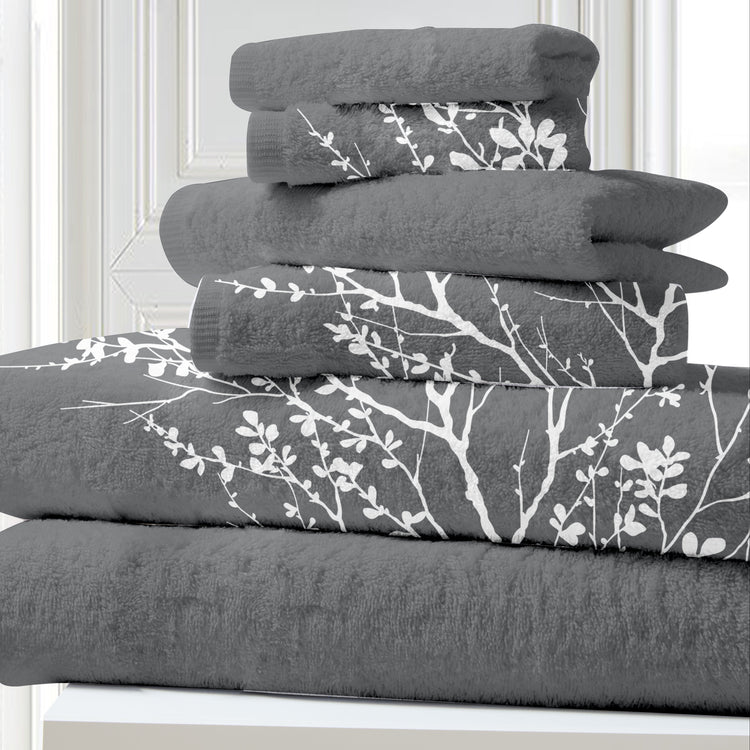 Stack of gray towels with white floral patterns on a white surface.