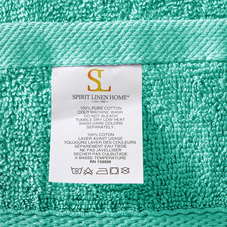 Teal towel with a label from Spirit Linen Home on a teal background