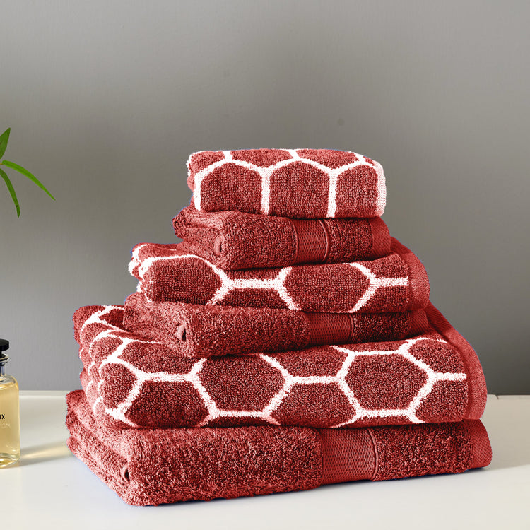 Stack of red towels with white geometric patterns on a gray background