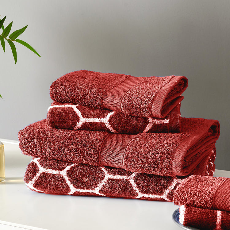 Stack of red towels with geometric pattern on a neutral background