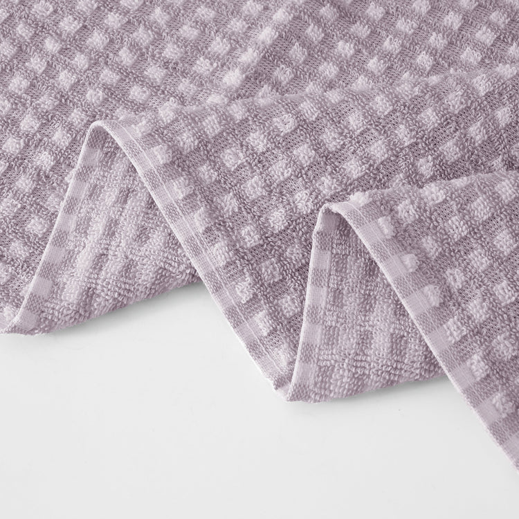 Folded purple towel with a checkered pattern on a white background