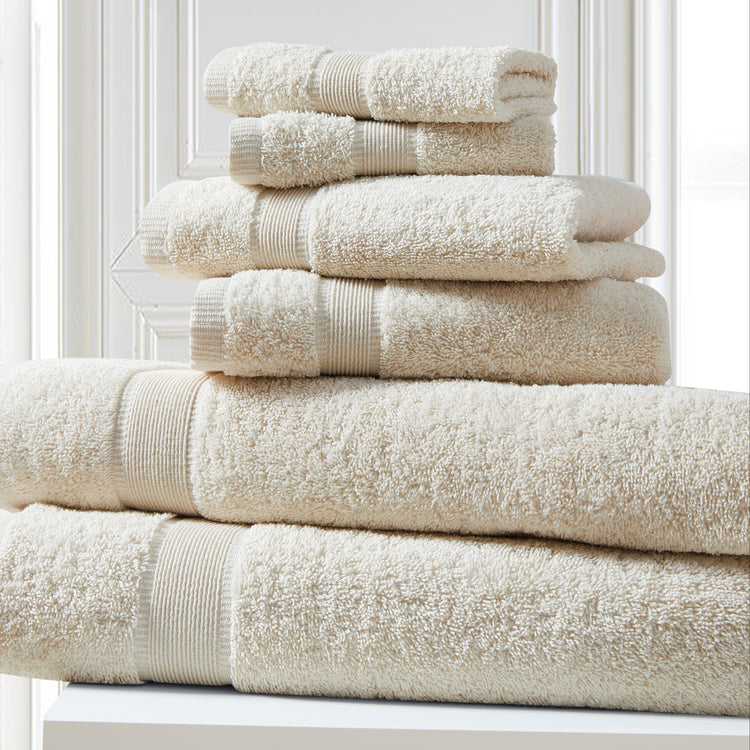 Stack of beige towels on a white surface with a light gray wall in the background