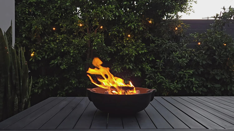 Fire pit on a wooden deck with greenery in the background