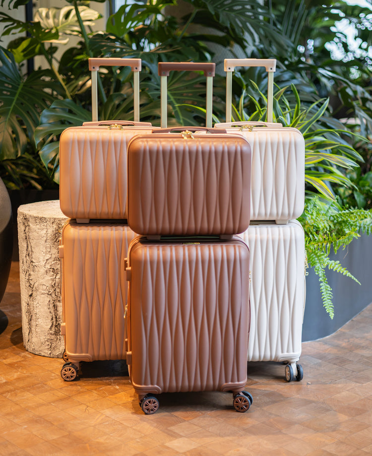 Set of suitcases in brown and white on a wooden floor with plants in the background