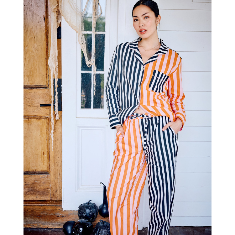 Woman wearing a striped outfit standing in front of a wooden door.