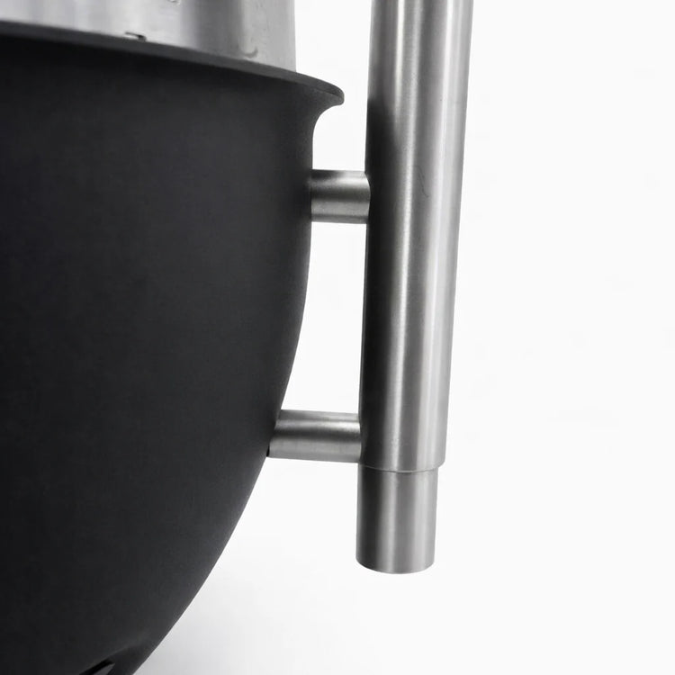 Close-up of a black pot with a stainless steel handle on a white background