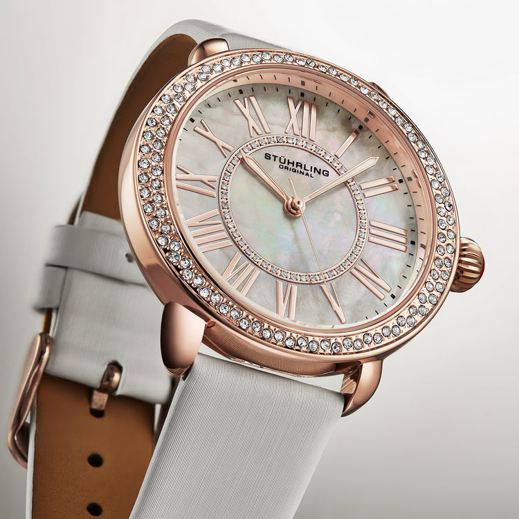 Luxury watch with rose gold case and white strap on a light background