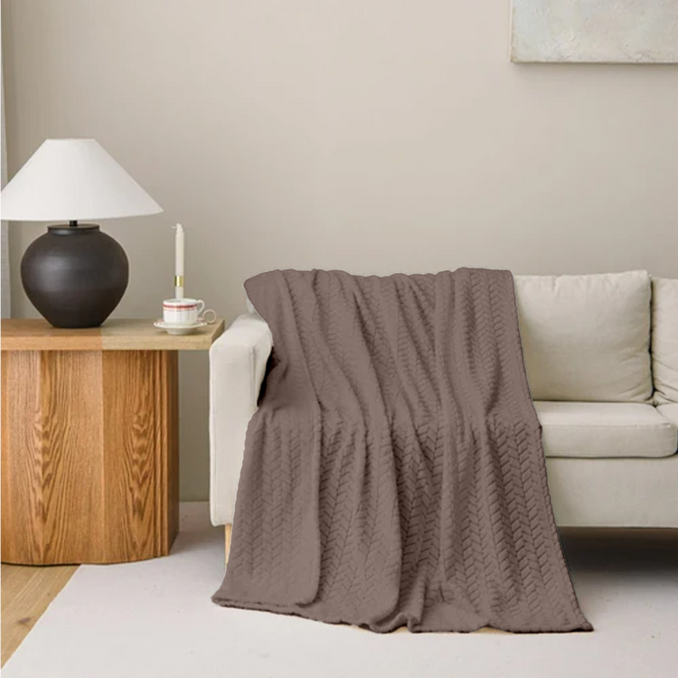 Brown textured blanket draped over a beige sofa in a living room setting.
