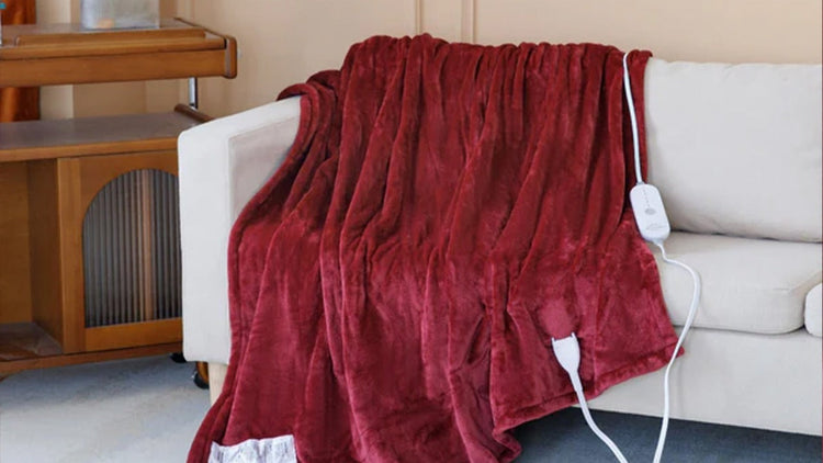 Red electric blanket draped over a white couch with power cord visible.