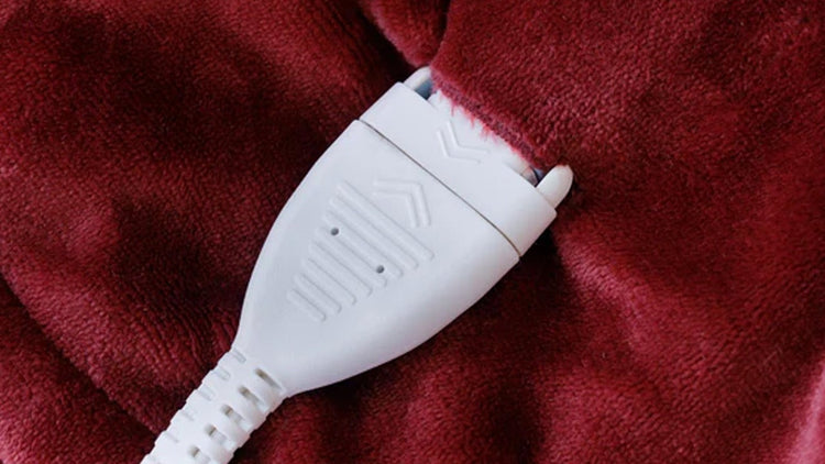 White electronic device with a cord on a red blanket
