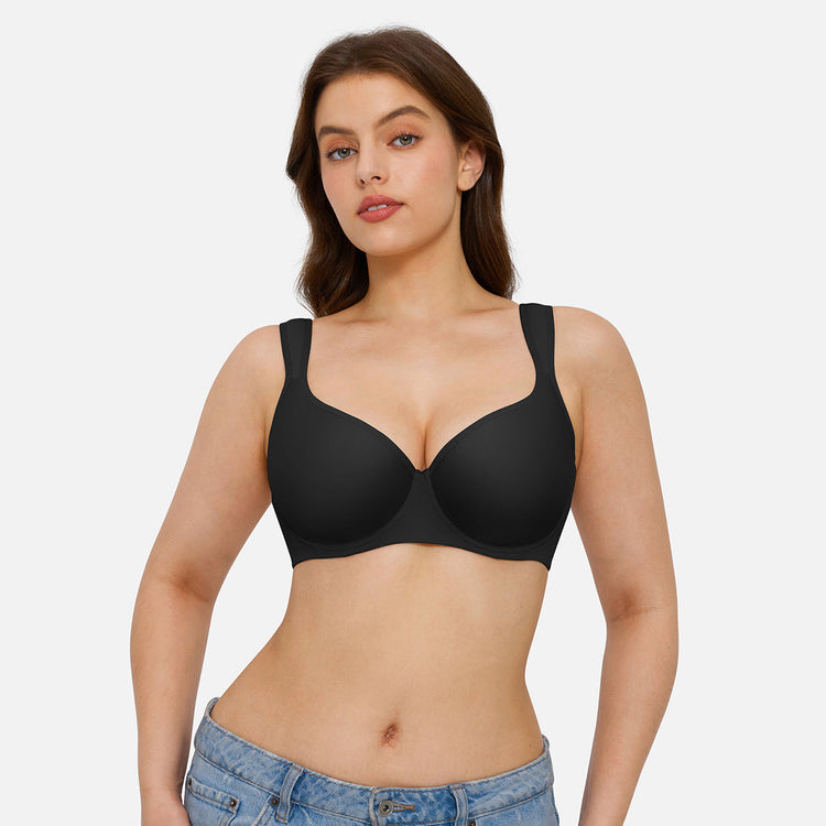 A woman modeling a black wireless underwire bra against a light gray studio background.