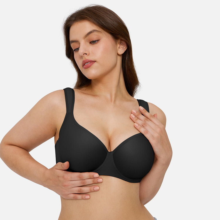 A woman modeling a black wireless bra against a light gray studio background.