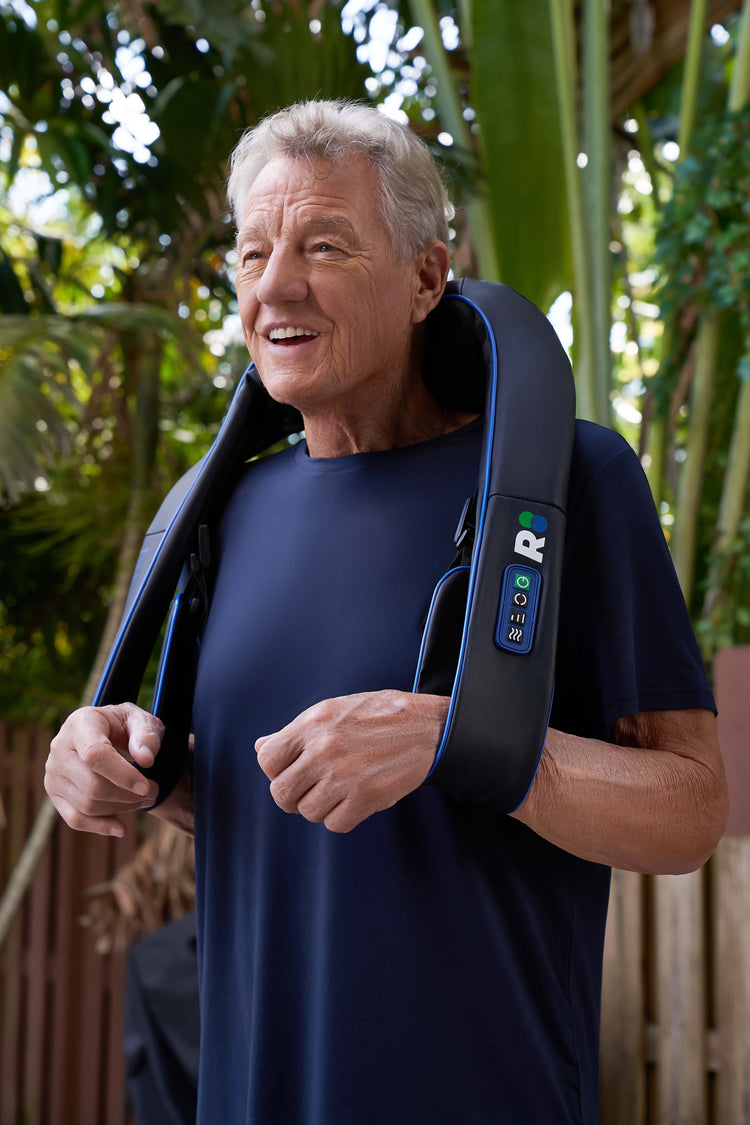 Man using a neck and shoulder massager outdoors with greenery in the background