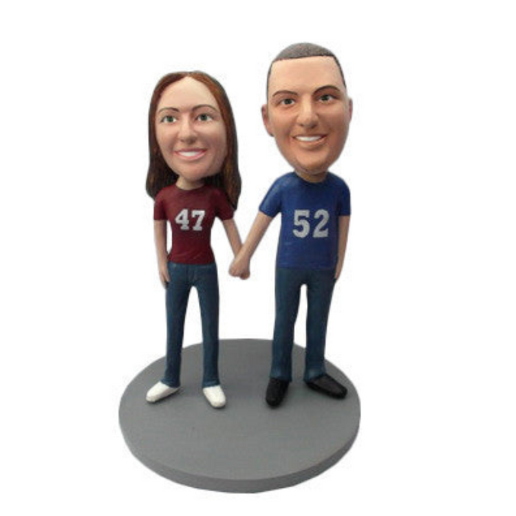 Bobblehead figures of a man and a woman wearing shirts with numbers, on a white background.
