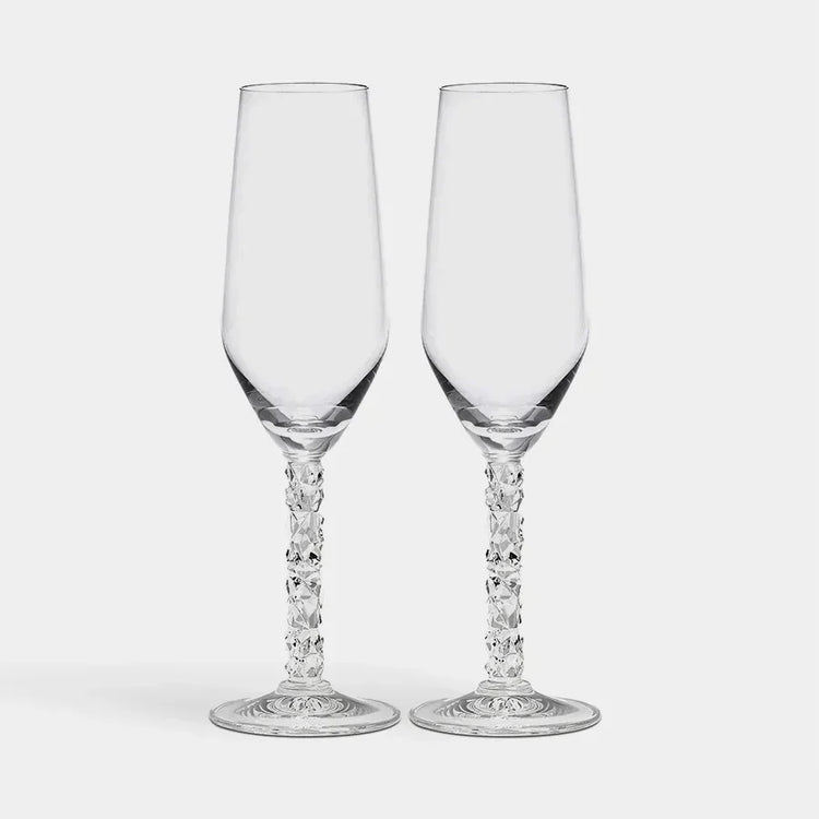 Two clear glass champagne flutes with intricate designs on a white background