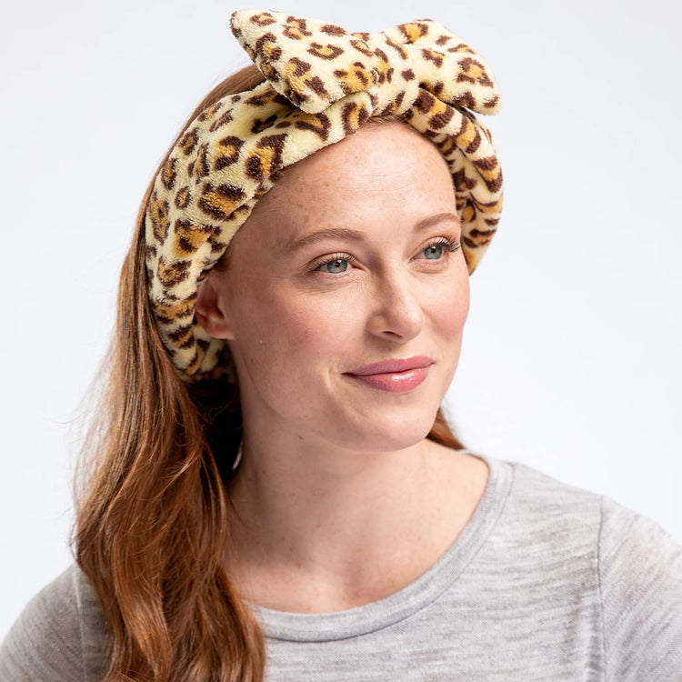 A woman wearing a multicolored geometric patterned headband with a large bow.