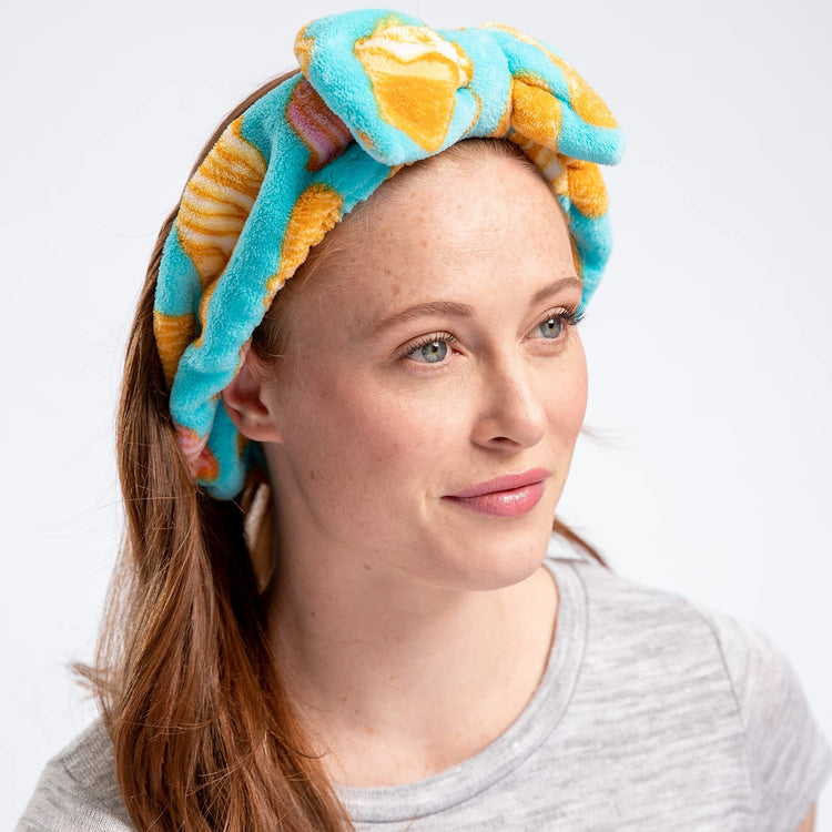 A woman wearing a multicolored geometric patterned headband with a large bow.