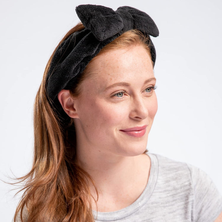 A woman wearing a multicolored geometric patterned headband with a large bow.